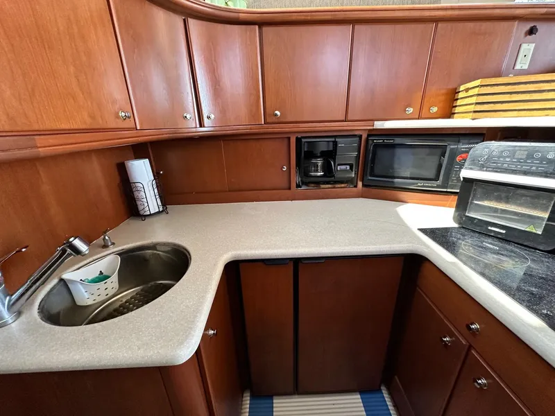 Slide: The Image of 2004 Silverton 38 Convertible yacht kitchen with sink, microwave, and wooden cabinets. - 44