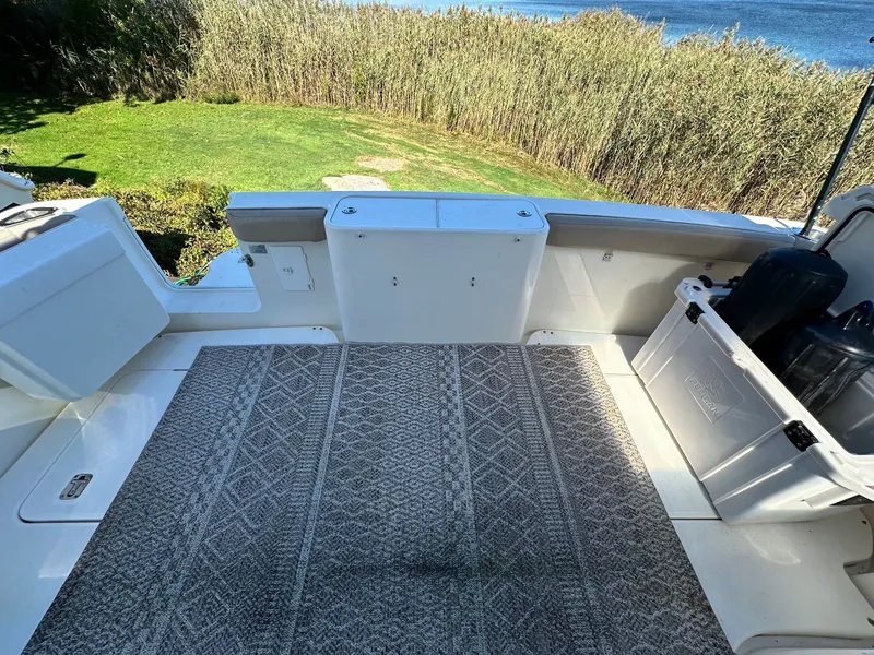 Slide: The Image of 2004 Silverton 38 Convertible boat deck with patterned rug and storage box, near water and reeds. - 9