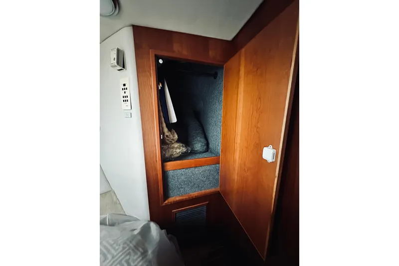 Slide: The Image of Wooden closet interior on a 2000 Riviera 40 yacht, featuring hanging clothes and storage. - 46