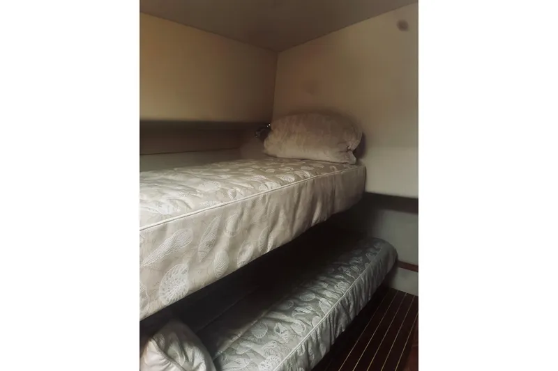 Slide: The Image of Interior of 2000 Riviera 40 yacht showing cozy bed and wooden cabinet. - 54