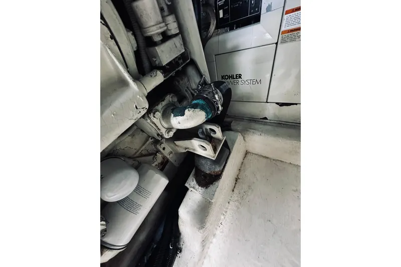 Slide: The Image of Engine compartment of a 2000 Riviera 40 boat, featuring mechanical components and hoses. - 64