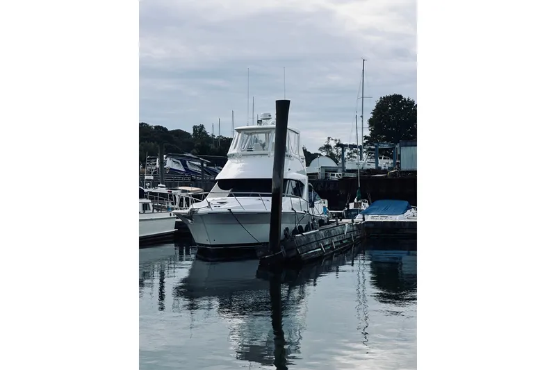 Slide: The Image of 2000 Riviera 40 yacht docked at a marina, surrounded by calm water and other boats. - 95