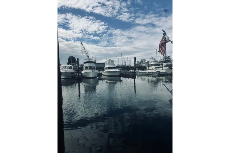 Slide: The Image of Boats docked at a marina under a cloudy sky, featuring a Riviera 40 from 2000. - 96