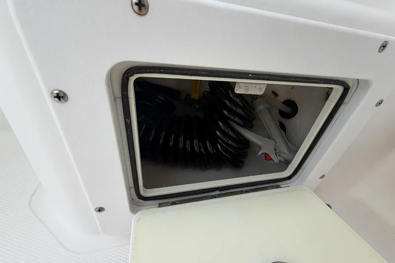 Slide: The Image of Storage compartment on a 1998 Cabo 31 Express boat, featuring coiled hose and nozzle. - 14