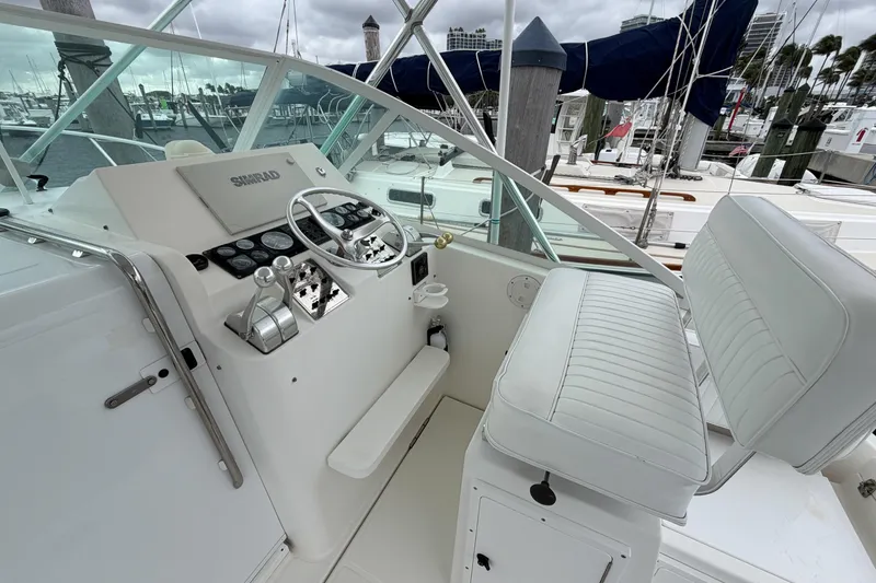 Slide: The Image of 1998 Cabo 31 Express boat helm with white seating and control panel at marina. - 15
