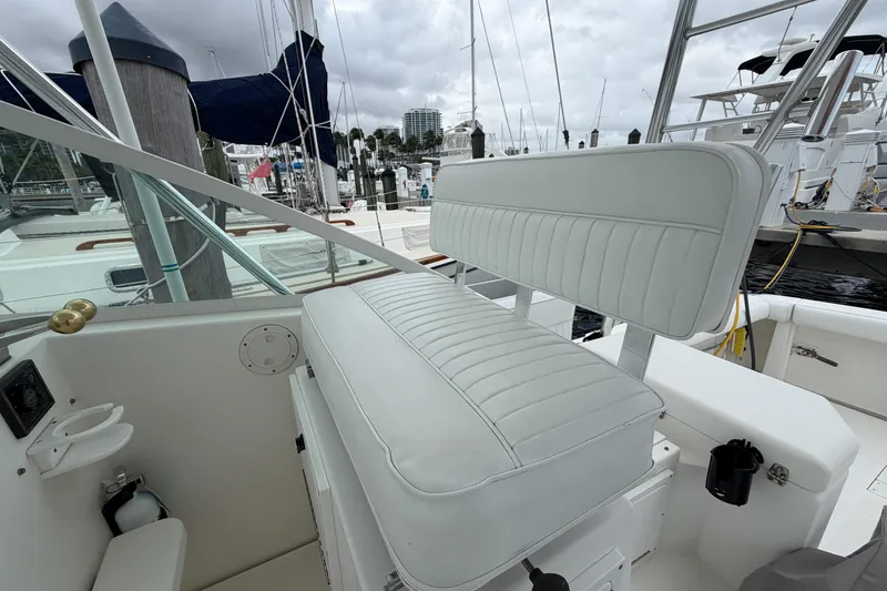 Slide: The Image of 1998 Cabo 31 Express boat interior with white cushioned seating at marina. - 16