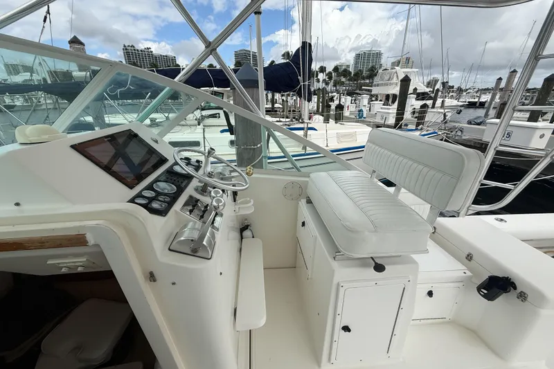 Slide: The Image of 1998 Cabo 31 Express boat helm with white seating and marina view. - 22