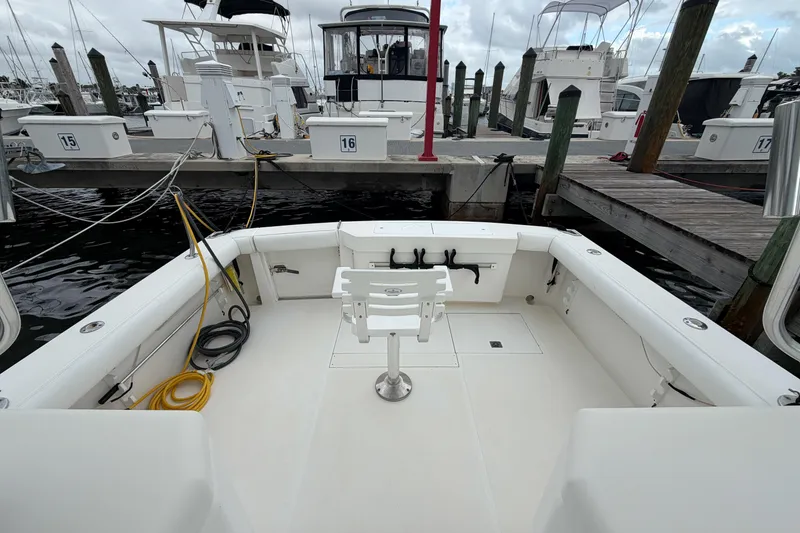 Slide: The Image of 1998 Cabo 31 Express boat docked at marina, featuring spacious deck and fishing chair. - 3