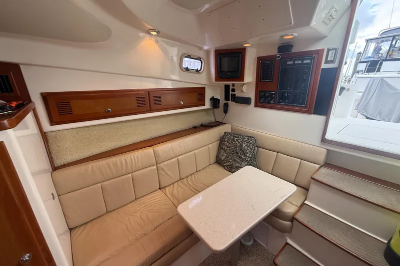 Slide: The Image of 1998 Cabo 31 Express cabin interior with beige seating, table, and control panel. - 34
