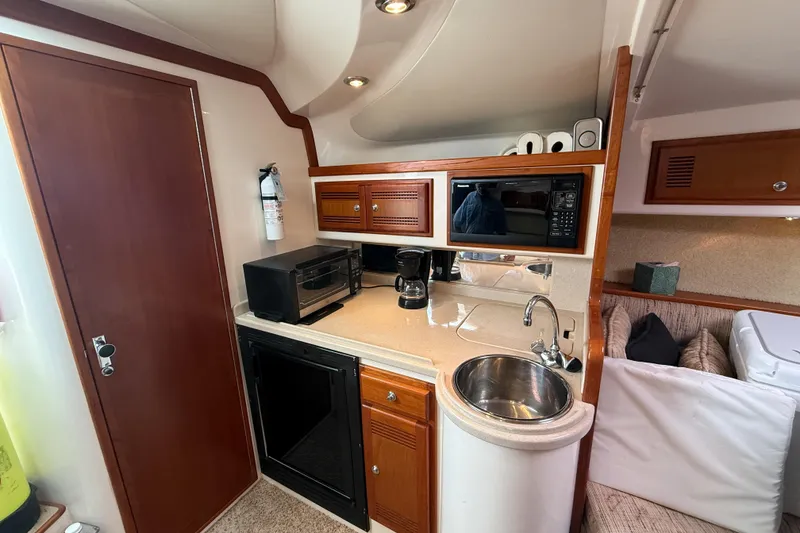 Slide: The Image of 1998 Cabo 31 Express yacht interior with kitchenette, featuring sink, microwave, and storage cabinets. - 35
