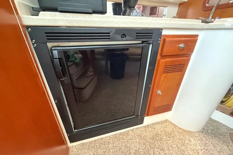 Slide: The Image of 1998 Cabo 31 Express boat interior with compact refrigerator and wooden cabinetry. - 36