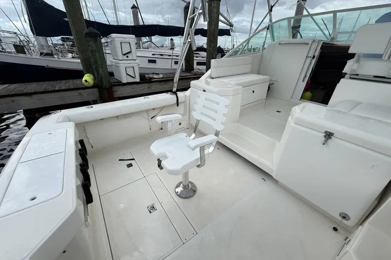 Slide: The Image of 1998 Cabo 31 Express boat interior with seating and fishing chair at dock. - 4