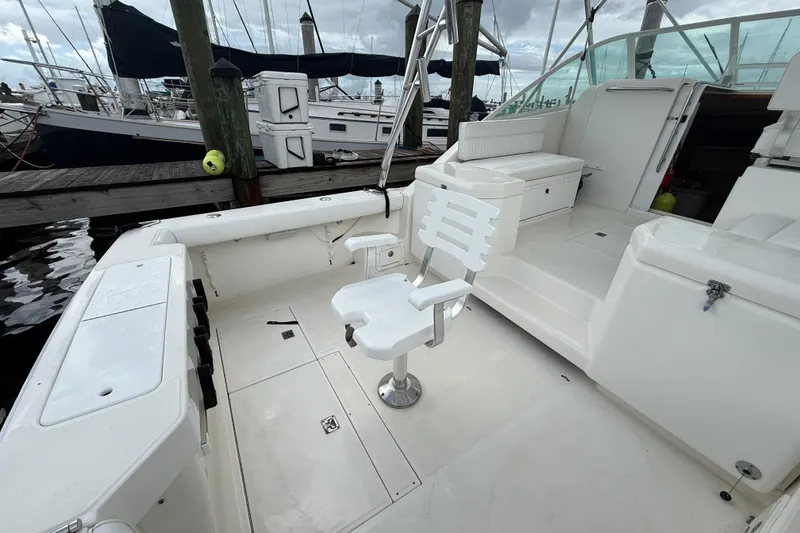 Slide: The Image of 1998 Cabo 31 Express boat interior with white seating and fishing chair at marina. - 5