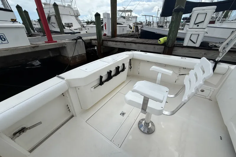 Slide: The Image of 1998 Cabo 31 Express boat interior with white seating at a marina dock. - 6