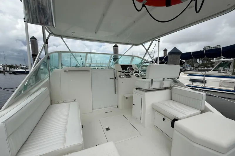 Slide: The Image of 1998 Cabo 31 Express boat interior with white seating and helm, docked at marina. - 8