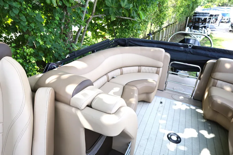 Slide: The Image of 2019 Harris Grand Mariner 250 boat interior with beige seating and lush greenery background. - 15