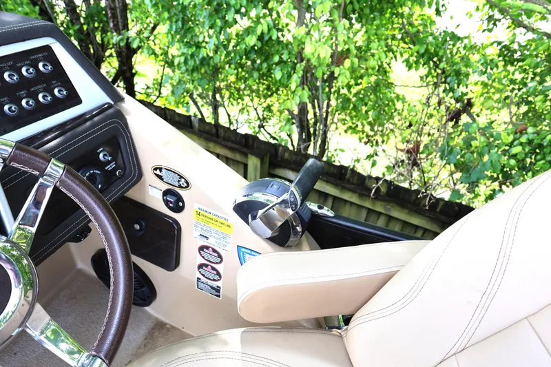 Slide: The Image of 2019 Harris Grand Mariner 250 helm with steering wheel and control panel, surrounded by greenery. - 19