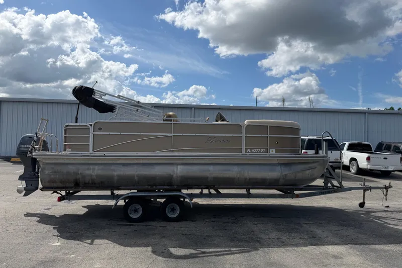 The Image of 2013 Berkshire 24RFC pontoon boat on trailer under cloudy sky. - 1