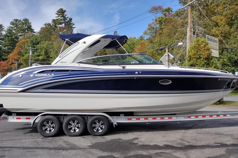 Slide: The Image of 2019 Formula 310 Bowrider boat on trailer, parked outdoors with trees in background. - 5