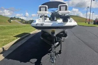 Slide: The Image of 2024 Tahoe 2150 boat on trailer, parked on asphalt, with grassy hills in the background. - 2