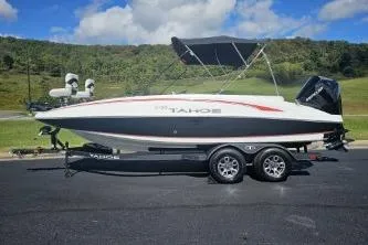 Slide: The Image of 2024 Tahoe 2150 boat on trailer, parked outdoors under a blue sky. - 4