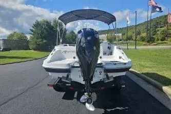 Slide: The Image of 2024 Tahoe 2150 boat with outboard motor on a sunny day, flags in background. - 5