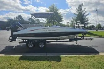 Slide: The Image of 2024 Tahoe 2150 boat on trailer, parked outdoors under a partly cloudy sky. - 6