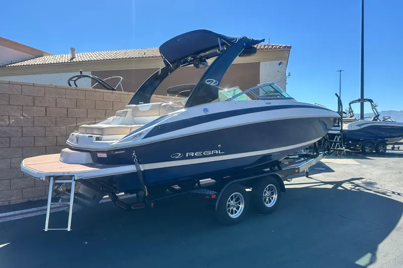 Slide: The Image of 2012 Regal 24 FasDeck boat on trailer, parked on sunny road. - 2