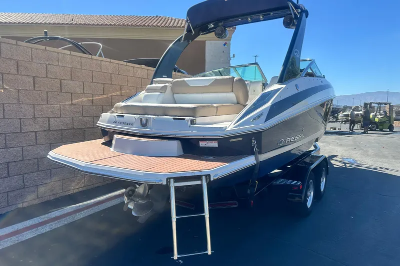 Slide: The Image of 2012 Regal 24 FasDeck boat on trailer, blue and white design, sunny day. - 3