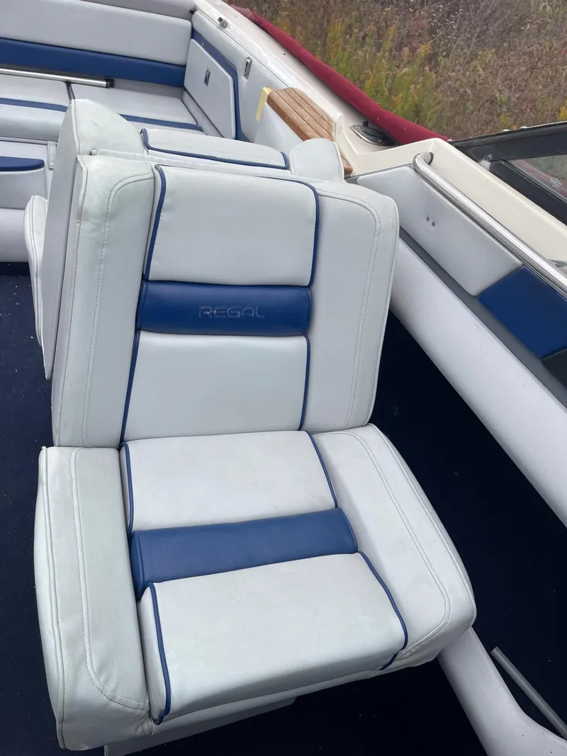 Slide: The Image of 1988 Regal boat interior with white and blue cushioned seats. - 20