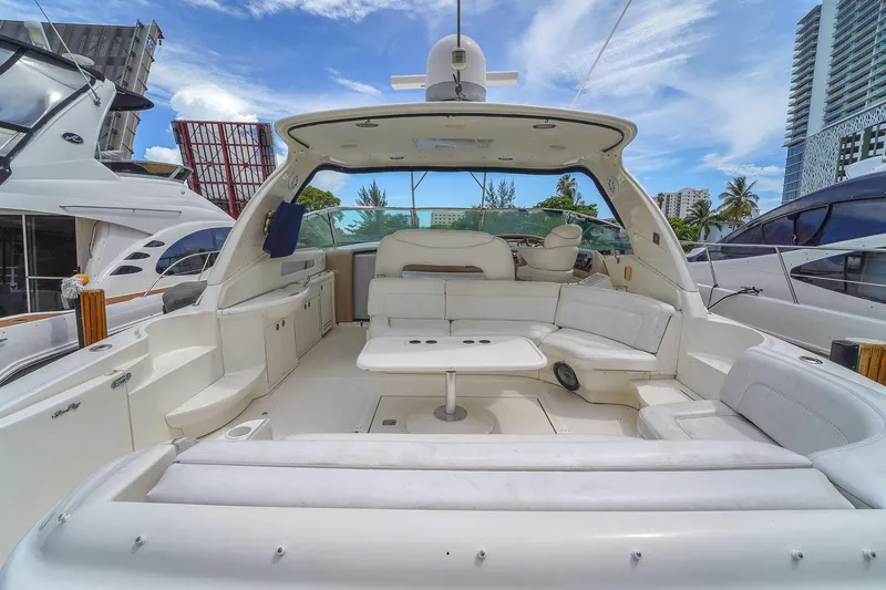 Slide: The Image of 2004 Sea Ray 460 Sundancer yacht interior with white seating and table, docked in a marina. - 6