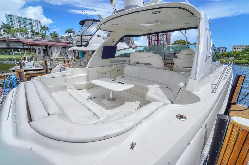 Slide: The Image of 2004 Sea Ray 460 Sundancer yacht with spacious white seating and table, docked by water. - 9