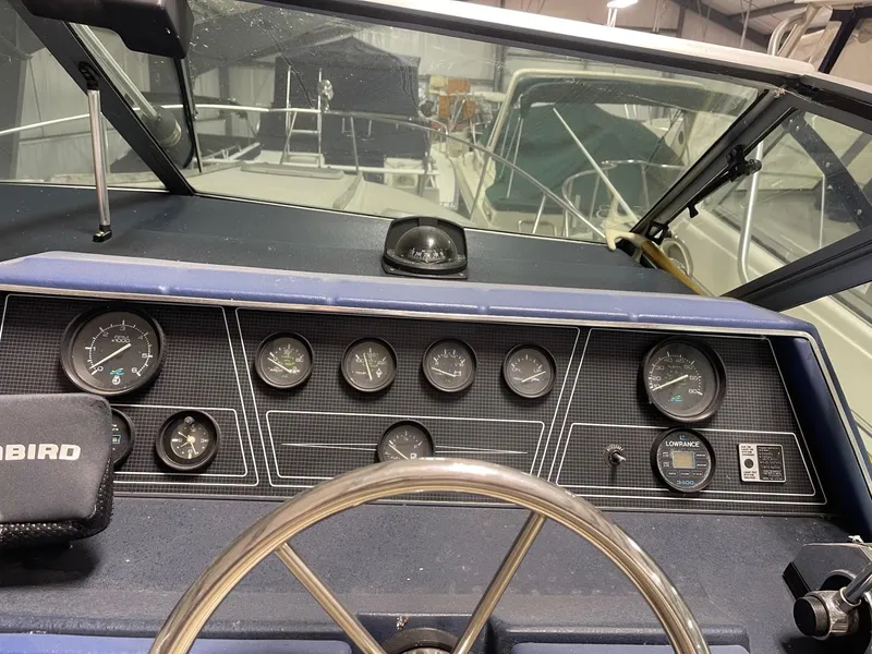 Slide: The Image of 1988 Sea Ray 268 Cruiser dashboard with gauges and steering wheel in a marina setting. - 10