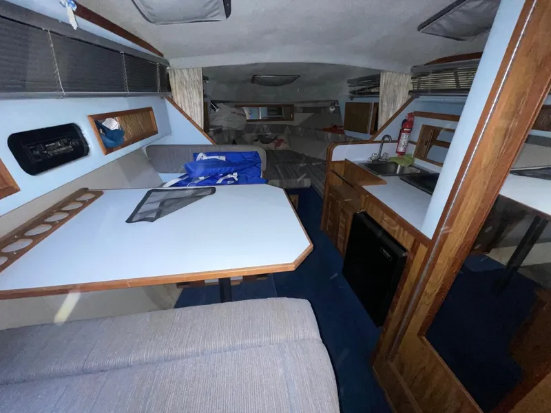 Slide: The Image of 1988 Sea Ray 268 Cruiser interior with dining area, kitchenette, and cozy seating. - 18
