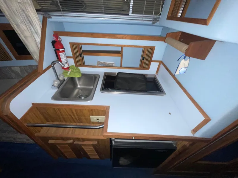 Slide: The Image of 1988 Sea Ray 268 Cruiser kitchen with sink, stove, and wooden cabinetry. - 23