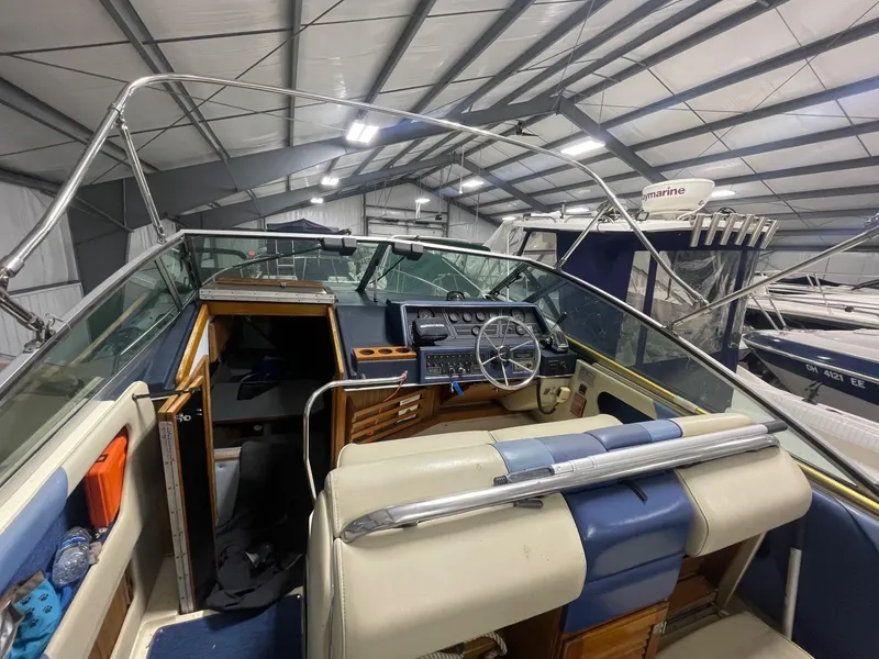Slide: The Image of 1988 Sea Ray 268 Cruiser interior with steering wheel and dashboard in a storage facility. - 26