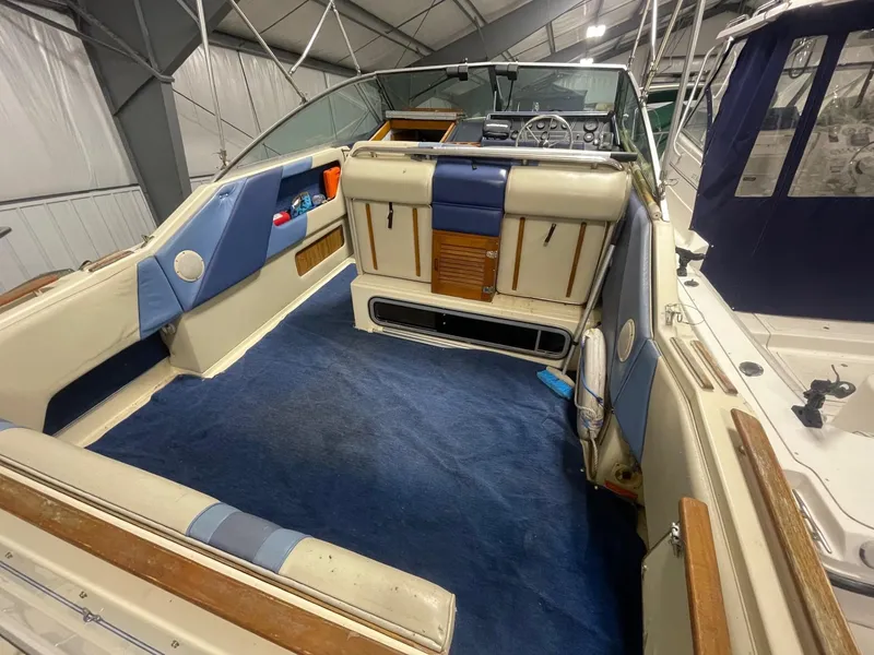 Slide: The Image of 1988 Sea Ray 268 Cruiser interior with blue and beige seating, docked in a covered marina. - 5