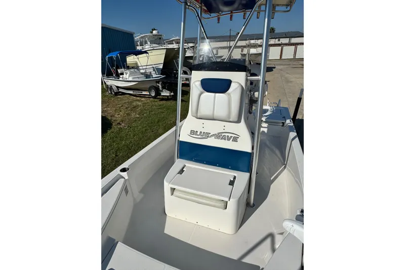 Slide: The Image of 2016 Blue Wave 2200 STL RISER boat with seating and console, parked outdoors. - 19