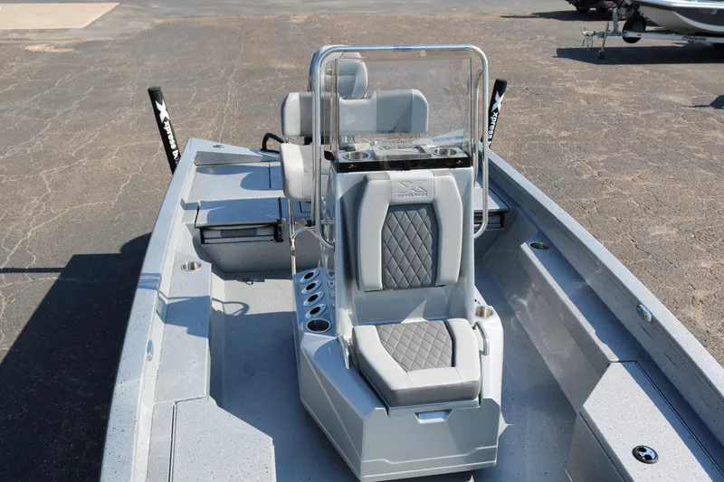 Slide: The Image of 2026 Xpress H20B Bay boat with steering console and seating, parked on pavement. - 11