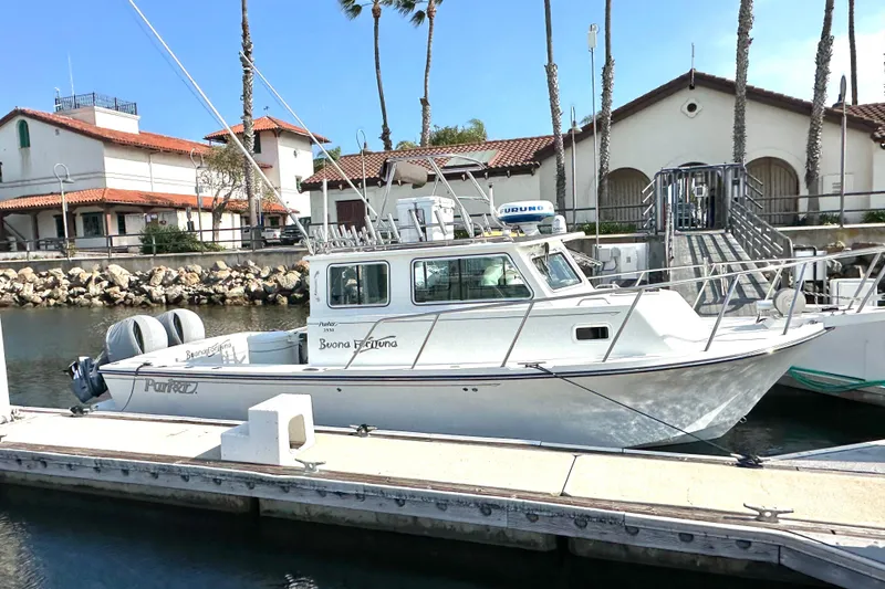 The Image of 2014 Parker 2530 Extended Cabin boat docked at marina with coastal buildings. - 0