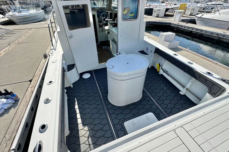 Slide: The Image of 2014 Parker 2530 Extended Cabin boat interior at marina, featuring spacious deck and seating. - 10