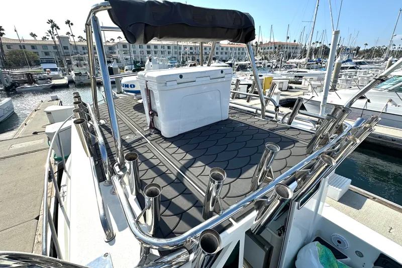 Slide: The Image of 2014 Parker 2530 Extended Cabin boat docked, featuring rod holders and a cooler on deck. - 12