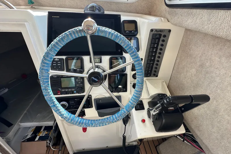 Slide: The Image of 2014 Parker 2530 Extended Cabin boat dashboard with steering wheel and control panel. - 19