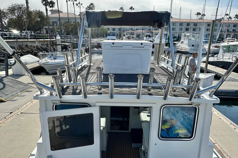 Slide: The Image of 2014 Parker 2530 Extended Cabin boat docked at marina, featuring spacious deck and rod holders. - 6
