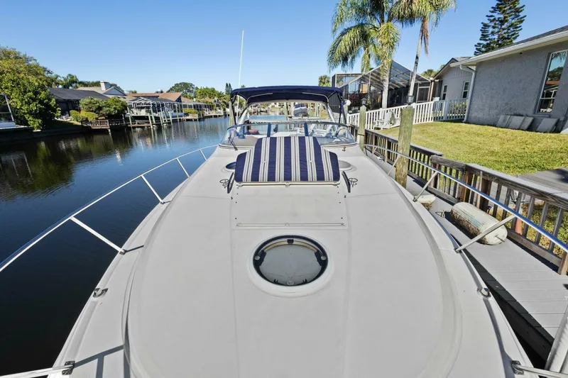 Slide: The Image of 2005 Regal Commodore 3560 yacht docked by a serene waterfront with palm trees. - 10