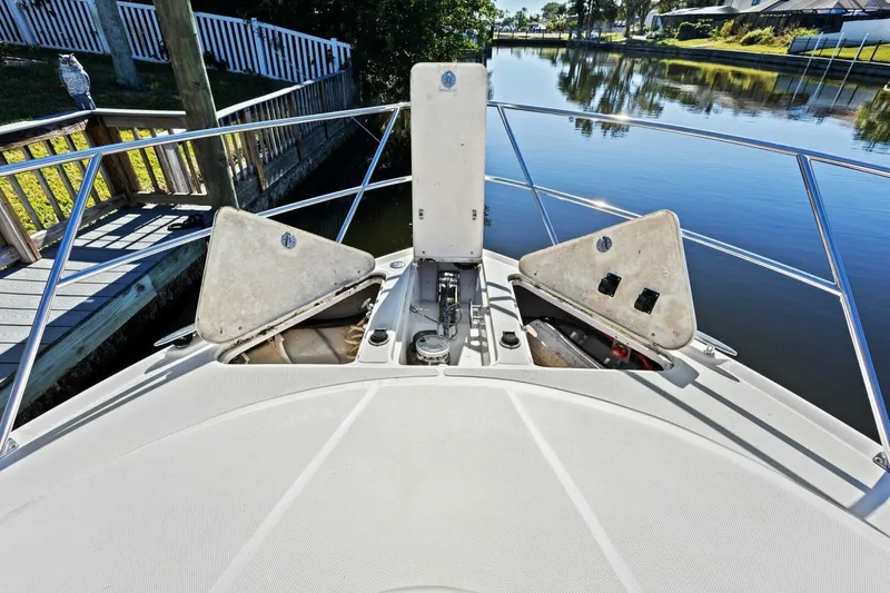 Slide: The Image of 2005 Regal Commodore 3560 boat deck with open storage compartments by a calm canal. - 11