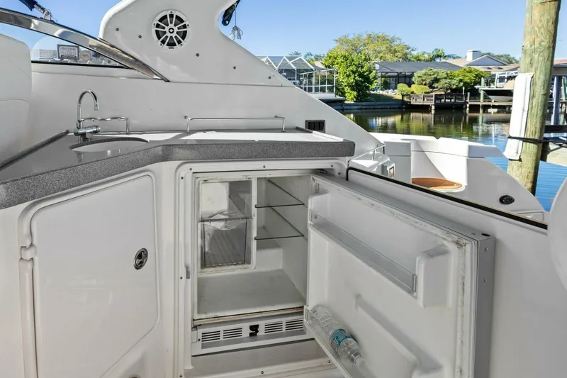 Slide: The Image of 2005 Regal Commodore 3560 yacht kitchenette with open fridge and sink, dockside view. - 17