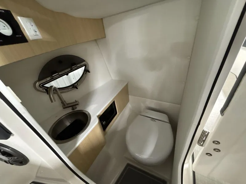 Slide: The Image of Compact bathroom in 2026 Regal LX4 boat with sink, toilet, and porthole window. - 16