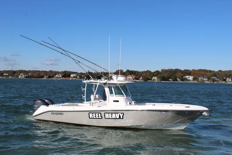 Slide: The Image of 2009 Everglades 320 Center Console boat on water, labeled "Reel Heavy," with scenic shoreline background. - 4