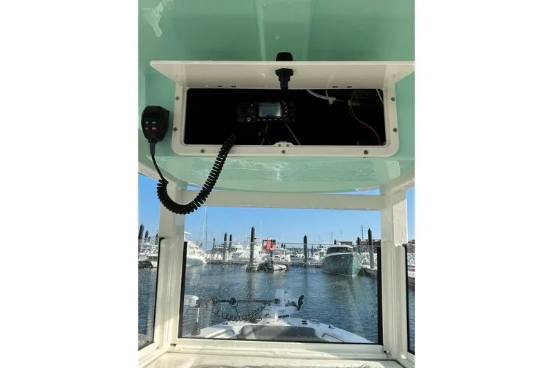 Slide: The Image of 2023 NauticStar 2602 Legacy boat console with radio, docked at marina. - 10